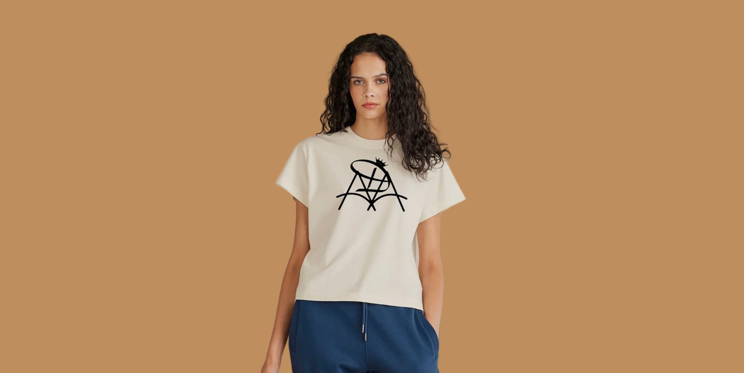 Woman wearing a white t-shirt with a black logo and blue pants on a beige background